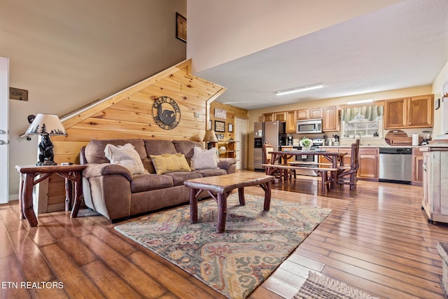 living room featuring sink, hardwood / wood-style floors, and wood walls