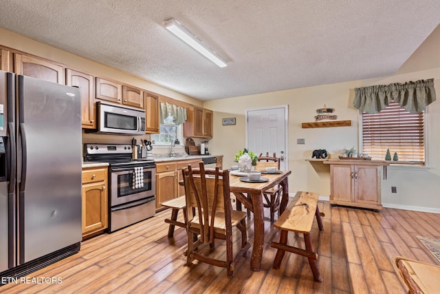 kitchen featuring appliances with stainless steel finishes, sink, a textured ceiling, and light wood-type flooring