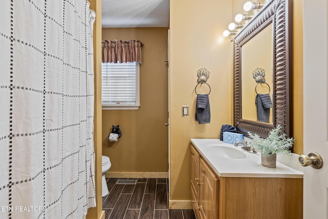 bathroom featuring vanity, toilet, and a textured ceiling