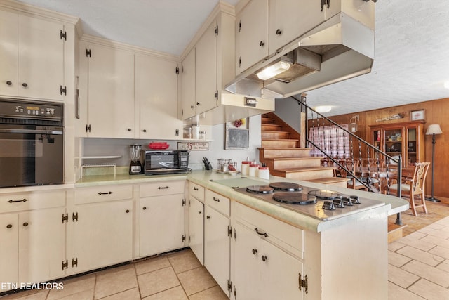 kitchen with kitchen peninsula, light tile patterned floors, wood walls, and black appliances