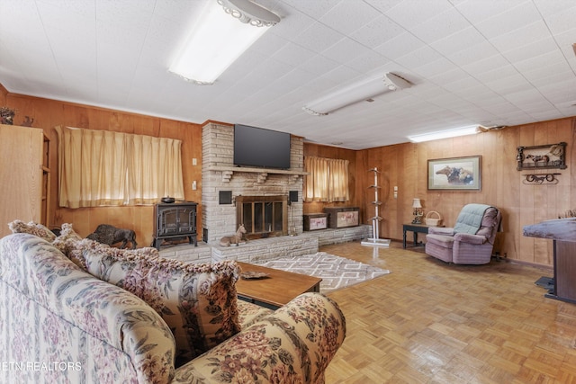 living room featuring light parquet flooring, wooden walls, and a wood stove