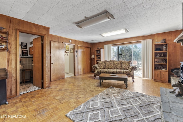 living room with light parquet floors and wood walls