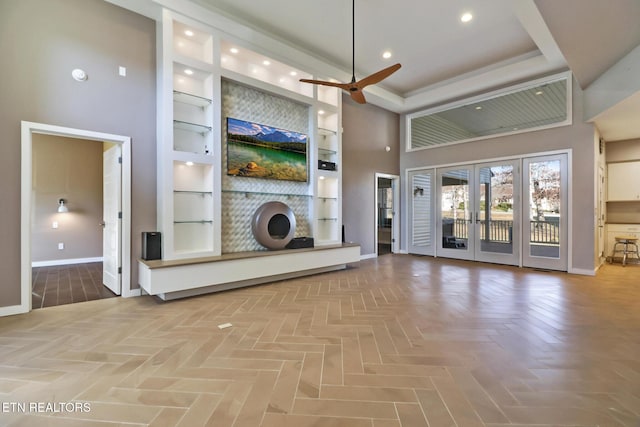 unfurnished living room featuring built in shelves, french doors, parquet floors, ceiling fan, and a high ceiling