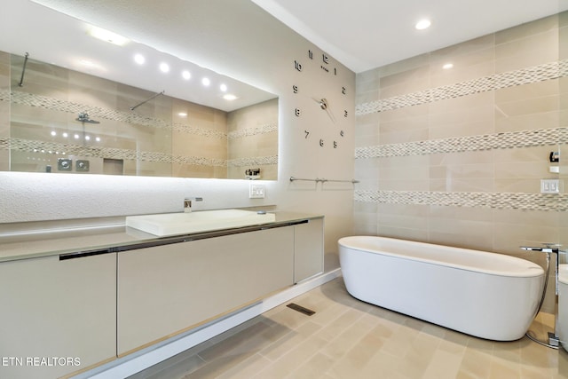 bathroom featuring vanity, independent shower and bath, and tile walls