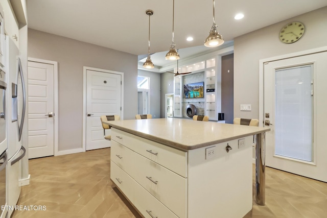 kitchen featuring hanging light fixtures, white cabinetry, a center island, and a breakfast bar