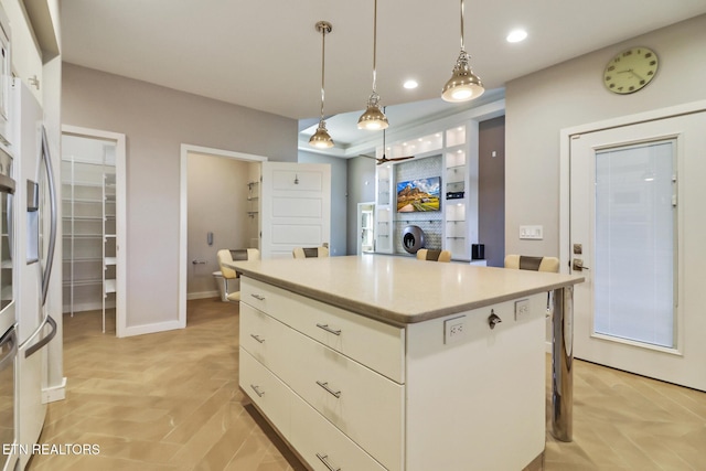 kitchen with decorative light fixtures, a breakfast bar, white cabinets, and a kitchen island