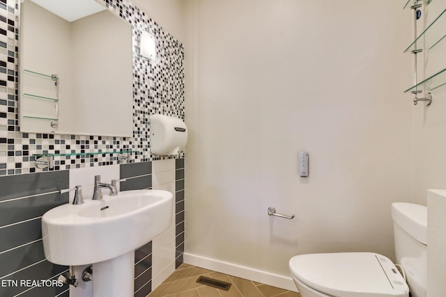 bathroom with tasteful backsplash, sink, tile patterned flooring, and toilet