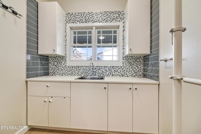 kitchen featuring tasteful backsplash, white cabinetry, and sink