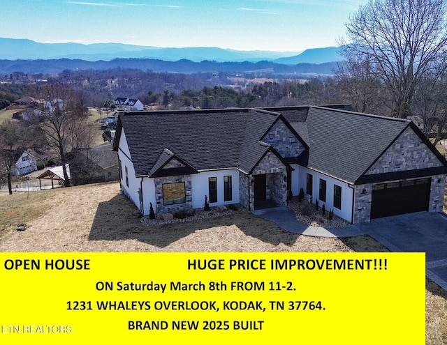 view of front of property with a garage, stone siding, a mountain view, and concrete driveway