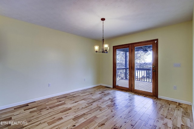 empty room featuring an inviting chandelier and light wood-type flooring