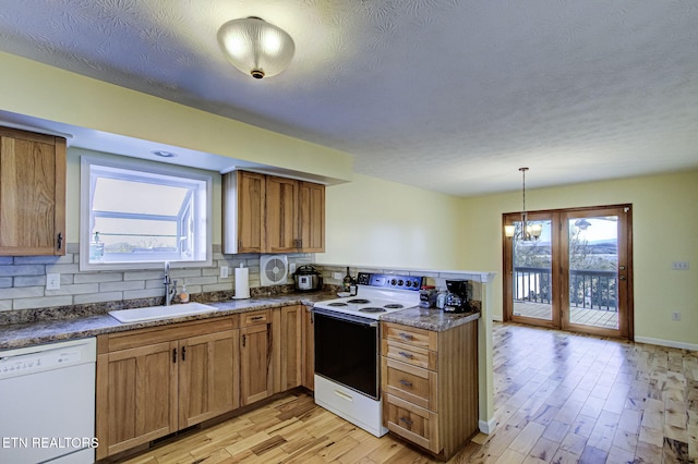 kitchen with sink, white appliances, light hardwood / wood-style floors, decorative backsplash, and decorative light fixtures