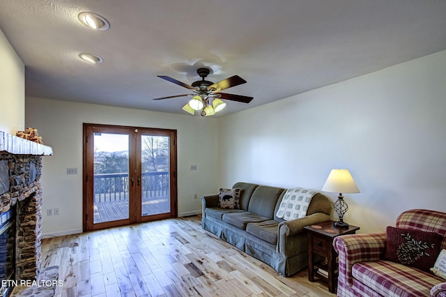 living room featuring ceiling fan, a fireplace, light wood-type flooring, and french doors