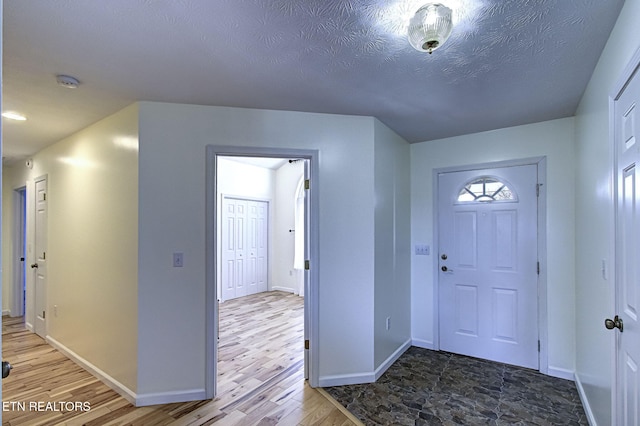 foyer entrance with hardwood / wood-style floors and a textured ceiling