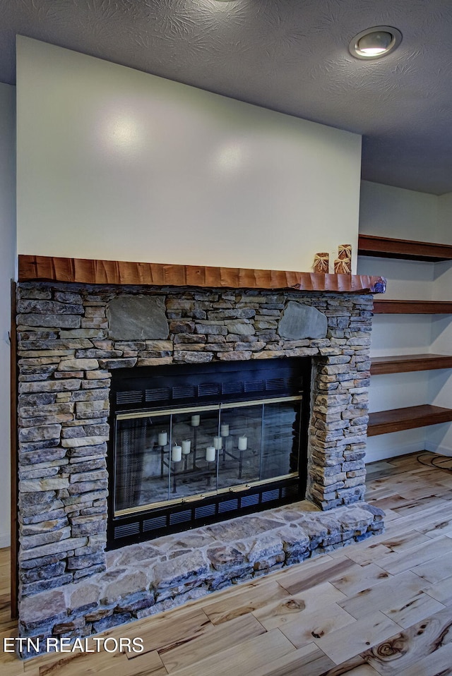 details with a stone fireplace, hardwood / wood-style floors, and a textured ceiling