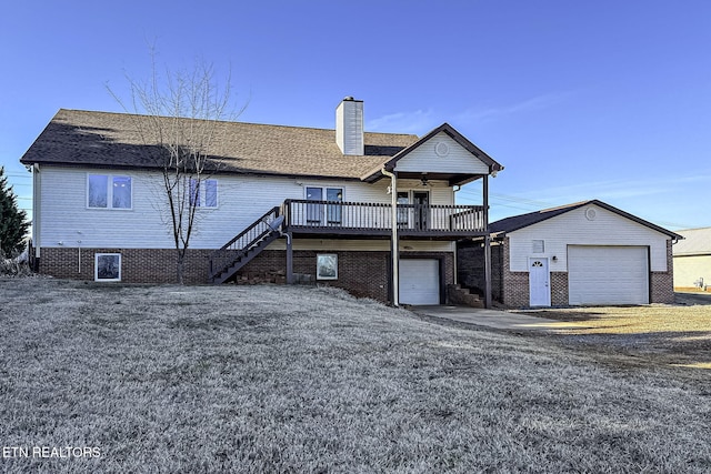 rear view of house featuring a garage, a wooden deck, and a lawn