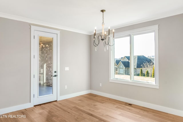 empty room featuring ornamental molding, a healthy amount of sunlight, a chandelier, and wood-type flooring