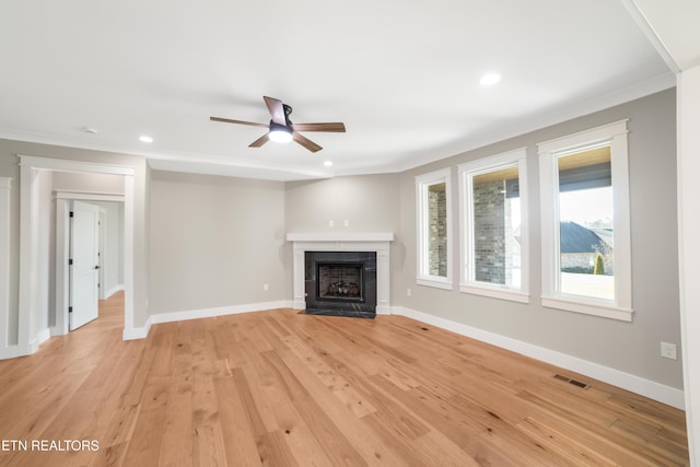 unfurnished living room featuring ceiling fan, ornamental molding, a tiled fireplace, and light wood-type flooring