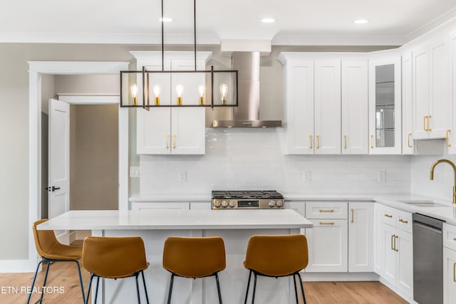 kitchen featuring pendant lighting, dishwasher, sink, a center island, and wall chimney exhaust hood