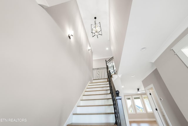 stairway featuring an inviting chandelier and ornamental molding