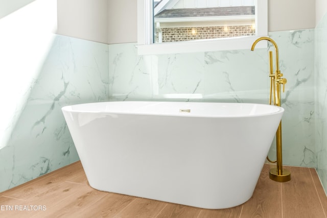 bathroom featuring hardwood / wood-style floors, a bathing tub, and a wealth of natural light