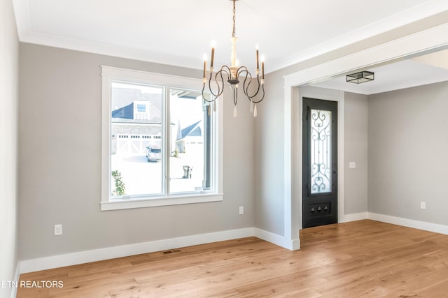 entryway with crown molding, a wealth of natural light, light hardwood / wood-style flooring, and an inviting chandelier