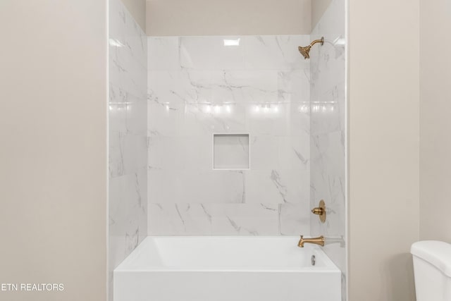 bathroom featuring toilet and tiled shower / bath