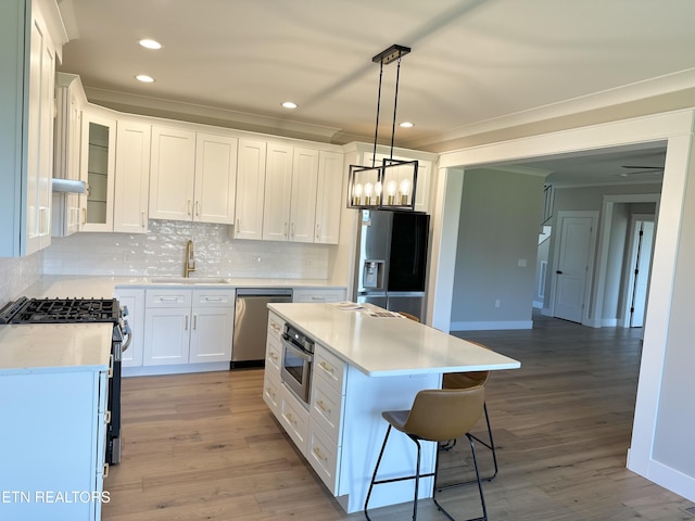 kitchen with a sink, decorative backsplash, crown molding, and stainless steel appliances