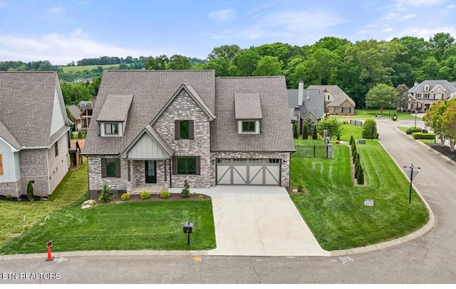 tudor-style house featuring a front yard, an attached garage, driveway, and stone siding