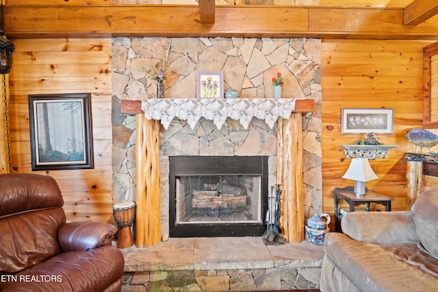 living area with wooden walls and a stone fireplace