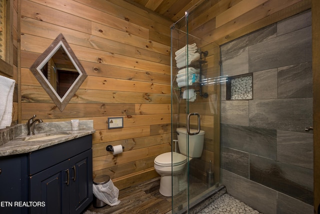 bathroom with walk in shower, toilet, vanity, wooden walls, and hardwood / wood-style floors