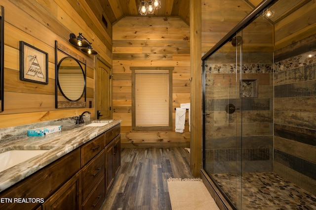 bathroom featuring vanity, hardwood / wood-style flooring, wooden walls, and a shower with door