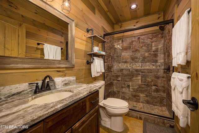 bathroom with vanity, a tile shower, wooden walls, and toilet