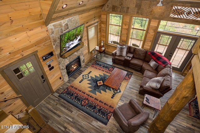 living room featuring a fireplace, high vaulted ceiling, hardwood / wood-style floors, and wood walls