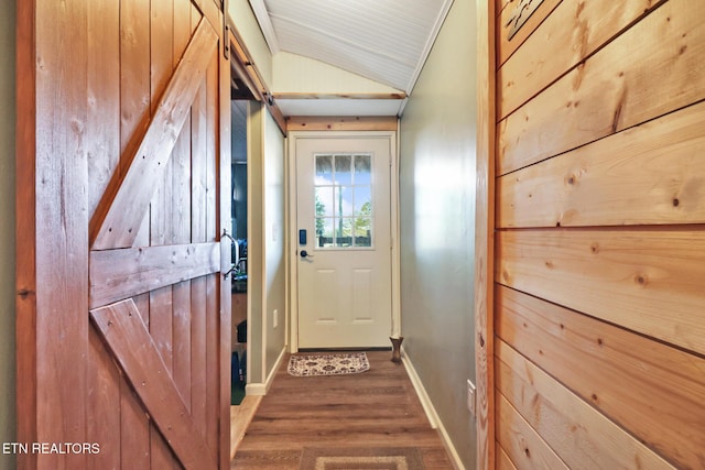 doorway with vaulted ceiling, a barn door, and dark hardwood / wood-style floors