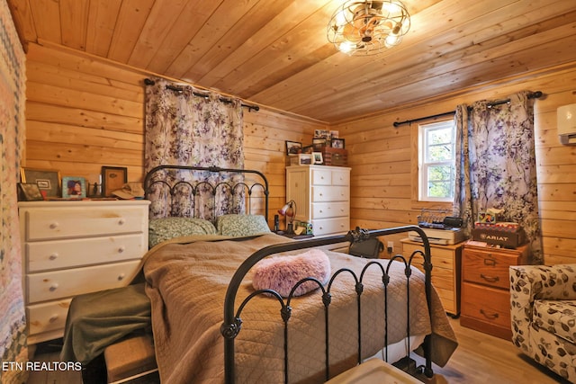 bedroom with wood ceiling, a wall mounted AC, light hardwood / wood-style flooring, and wood walls