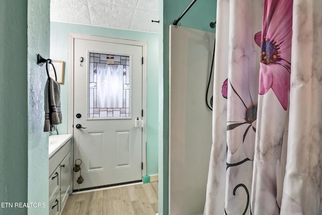 bathroom with wood-type flooring, a shower with shower curtain, and vanity