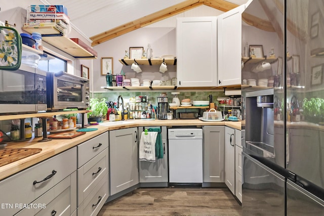 kitchen with vaulted ceiling, tasteful backsplash, white cabinets, dark hardwood / wood-style flooring, and white dishwasher