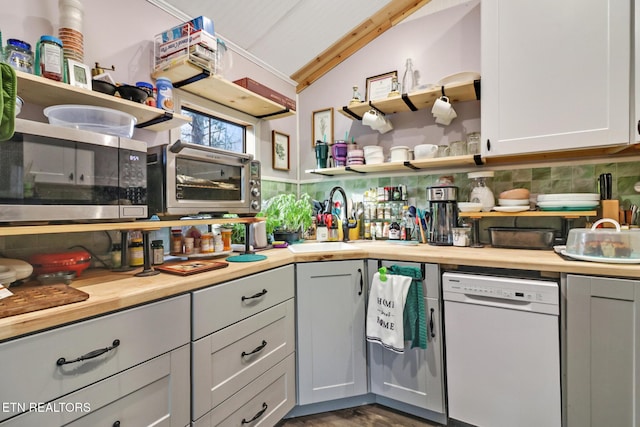 kitchen featuring dishwasher, sink, wood counters, and decorative backsplash