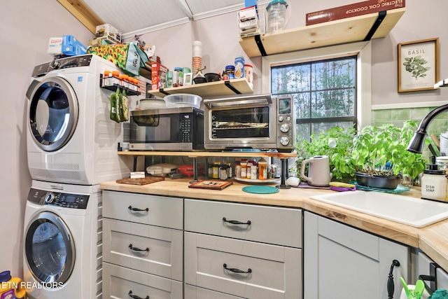 laundry room with stacked washer / drying machine and sink