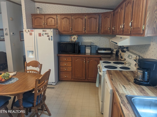 kitchen with crown molding, white appliances, butcher block counters, and vaulted ceiling