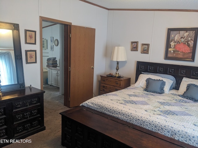 bedroom with crown molding, ensuite bath, and dark colored carpet