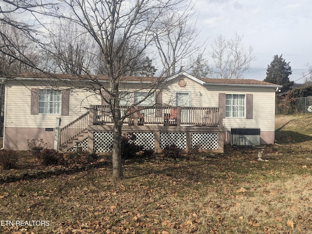 rear view of house with a wooden deck, central AC unit, and a lawn