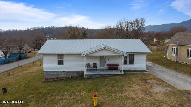 rear view of house featuring a mountain view, a lawn, and covered porch