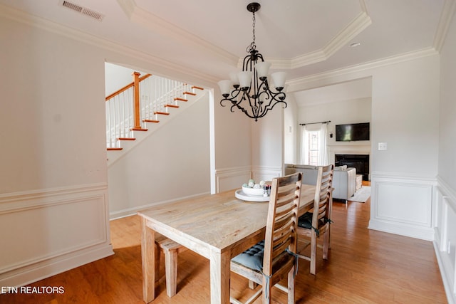 dining room featuring hardwood / wood-style floors, ornamental molding, and a chandelier