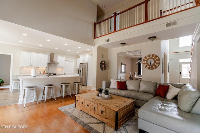 living room with ornamental molding, light hardwood / wood-style floors, and a wealth of natural light