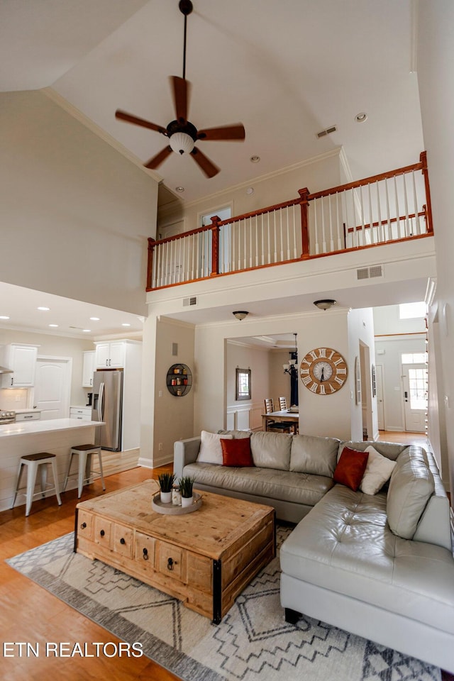 living room with crown molding, ceiling fan, high vaulted ceiling, and light hardwood / wood-style flooring