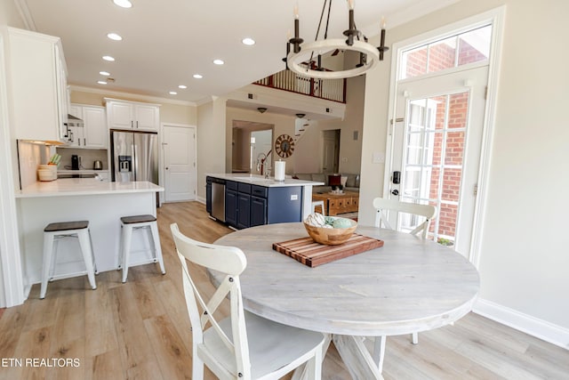 dining area with a notable chandelier, ornamental molding, and light wood-type flooring