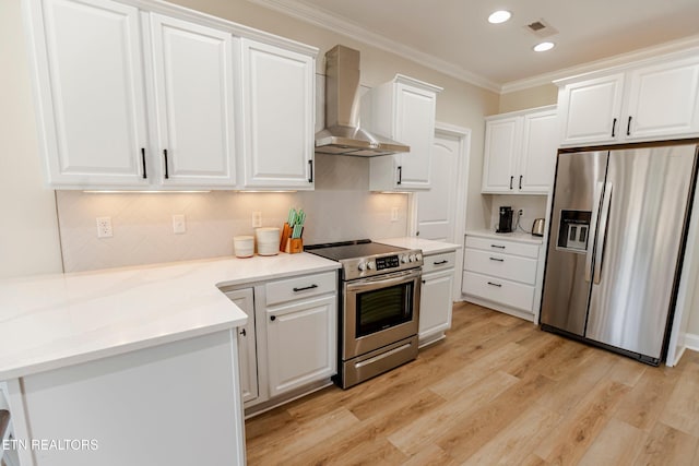 kitchen with white cabinetry, light hardwood / wood-style flooring, ornamental molding, appliances with stainless steel finishes, and wall chimney range hood