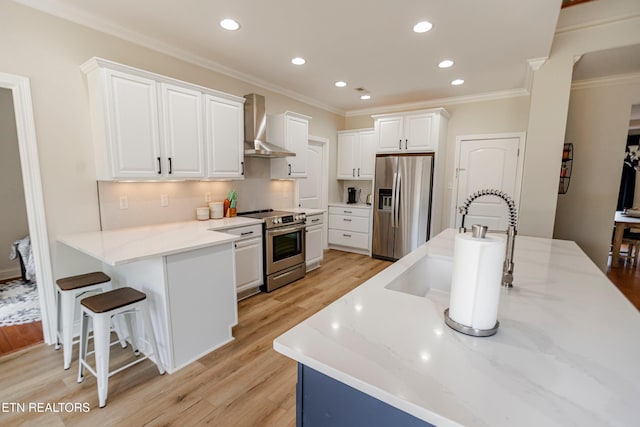 kitchen featuring white cabinetry, wall chimney range hood, stainless steel appliances, and light hardwood / wood-style floors