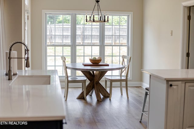 dining space with sink, a chandelier, and light hardwood / wood-style flooring